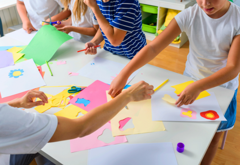 A group of children making paper crafts in a classroom