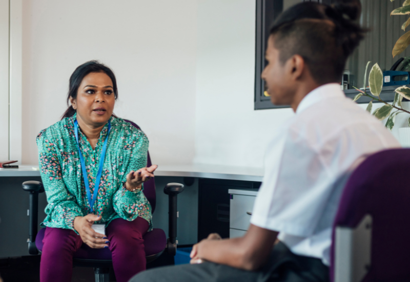 A woman talking to a student in an office.