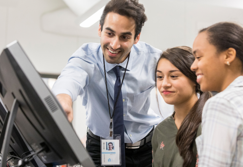 Educator looks on at computer with two colleagues