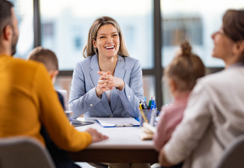 A woman sitting at a table in front of a group of parents and students
