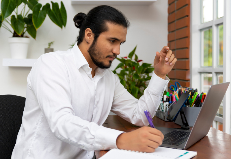 A man sitting at a desk working on a laptop
