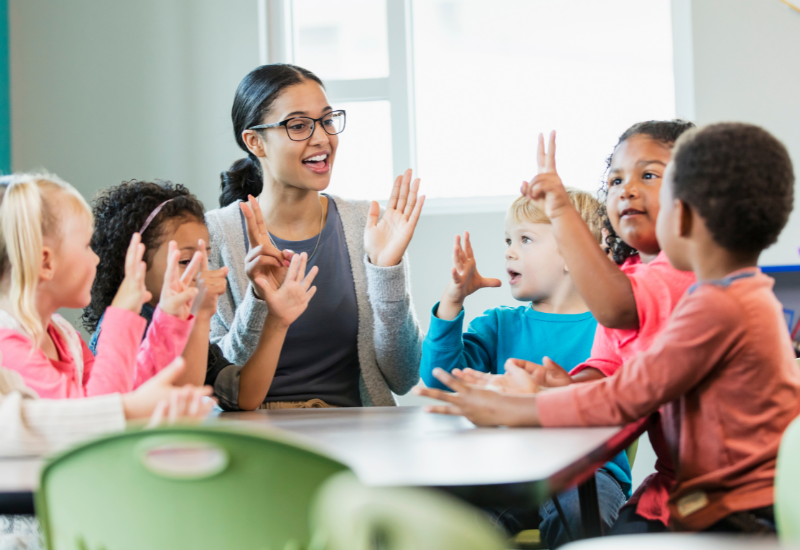 A group of children are sitting around a table in a classroom.
