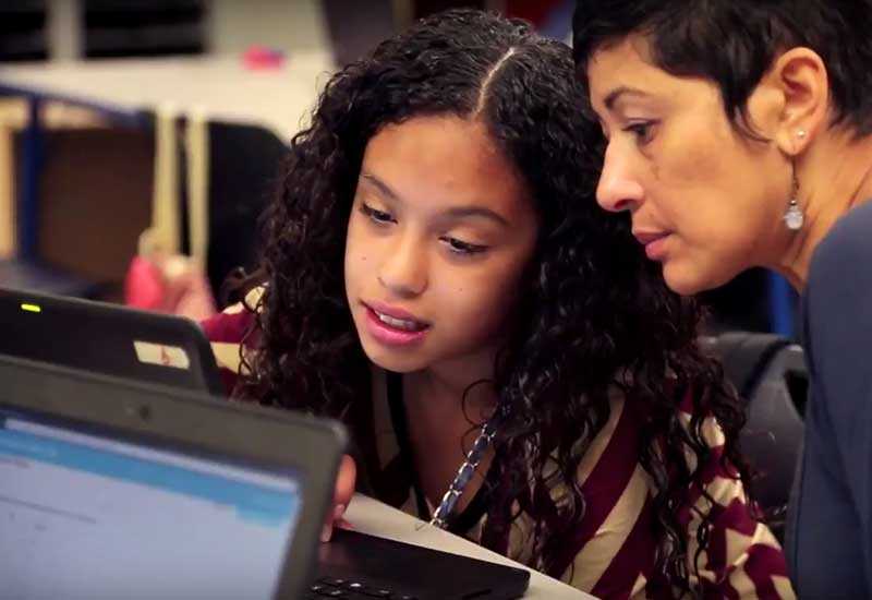Student and teacher looking at a laptop screen together