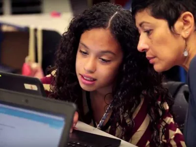 Student and teacher looking at a laptop screen together
