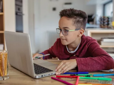 A young boy sitting at a table using a laptop computer
