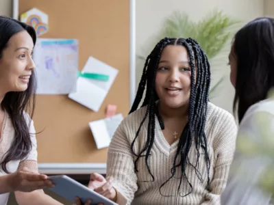 Two adults and a student talking to each other in an office.
