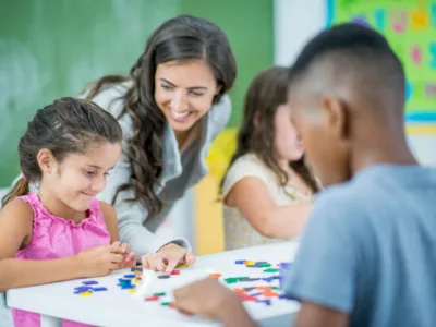 Teacher works with students on project in classroom
