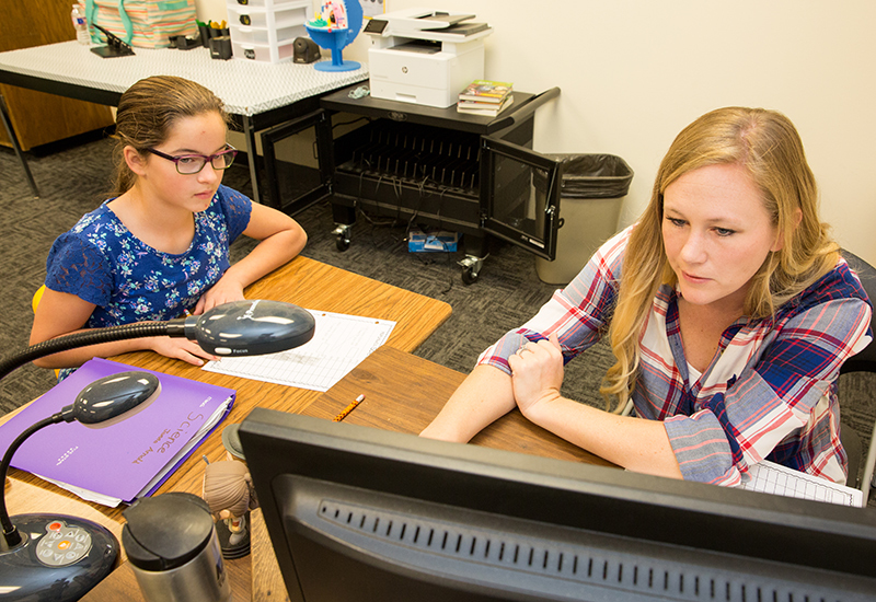 Teacher and student look on at computer screen