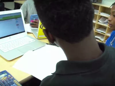 Photo of students working together with notebook and devices
