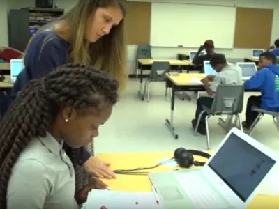 Photo of student and teacher working together at desk
