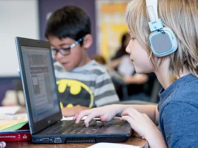 Student types on laptop while wearing headphones
