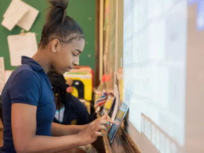 Student works off of tablet in front of interactive white board
