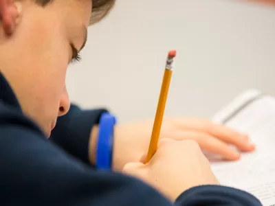Student writes on paper with pencil

