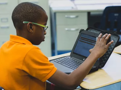 Student looks at laptop, touching the screen while working
