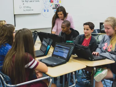 Teacher looks on as group of students work together

