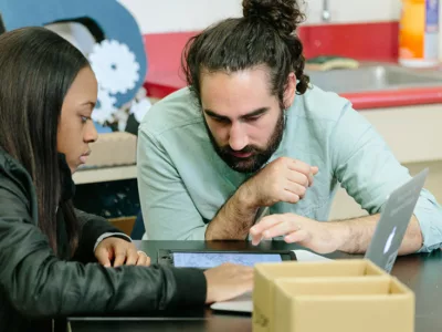 Teacher and student look down at tablet
