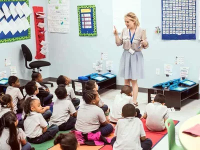 Photo of teacher standing in front of class teaching to group of seated students
