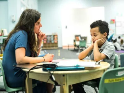 Photo of student and teacher holding a conference at a table
