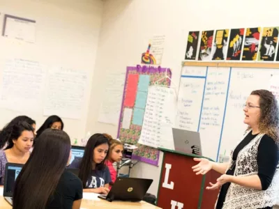 Photo of teacher speaking to a group of students in classroom
