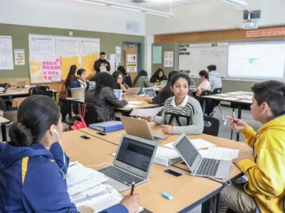 Photo of multiple groups of students seated around tables in a classroom
