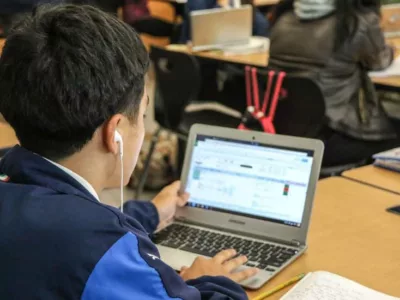 Photo of student and his laptop with screen showing data dashboard
