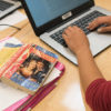 Person types on laptop, set beside a book of Romeo and Juliet